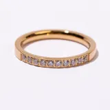 Anillo de acero inoxidable con baño dorado, estilo alianza, con una hilera de cristales engarzados en la parte superior.