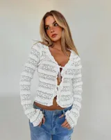 Blusa de encaje blanco con transparencias, escote en V, mangas largas y cierre frontal con finos lazos ajustables.