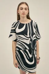 Top de escote redondo y manga corta, con corte asimétrico en la espalda. Confeccionado en lino viscosa, con estampado abstracto en blanco y negro.