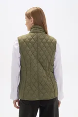 Chaleco acolchado de diseño capitoneado en color verde militar, con cuello alto, cierre frontal con botones a presión y bolsillos laterales con solapa y detalles en contraste.