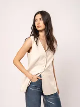 Chaleco color crema de lino con corte sastrero, largo a la cadera, forro interno, botones delanteros, silueta levemente entallada y tajo cruzado en la espalda.