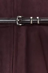 Chaqueta color beige con efecto ante, cuello redondo, manga larga y cierre frontal con cremallera. Presenta un bajo en evasé y un cinturón fino de cuero marrón oscuro con hebilla metálica.