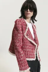 Saco corto rojo con textura tweed y cuello con solapa con flecos blancos.