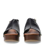 Sandalias de cuero negro con plataforma y taco cuadrado efecto madera. Presentan una tira frontal ancha con tachas metálicas decorativas y una pulsera ajustable con hebilla en el tobillo.