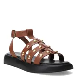 Sandalias tipo franciscana de cuero color marrón, con tiras decoradas con tachas metálicas doradas. Presentan una base de plataforma plana color negro y cierre con hebilla ajustable en el tobillo.