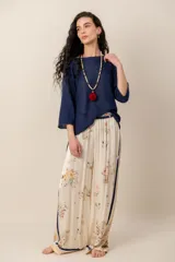 Pantalón fluido de tiro alto en color crudo con estampado floral en tonos naranjas y detalles de franjas laterales en azul marino.