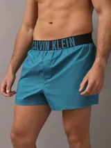 Pack de dos bóxer Calvin Klein de algodón elástico, uno negro y otro azul petróleo, con cinturilla elástica con logo de la marca.