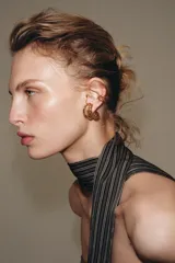 Set de cuatro pendientes metálicos dorados que incluye un par de aros triples con cierre de tuerca, un earcuff de aro doble y un earcuff de aro triple con detalle de cristal.