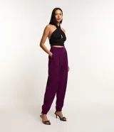 Pantalón jogger color violeta confeccionado en crepé, con pliegues, bolsillos tipo cuchillo y cierre delantero con cremallera.