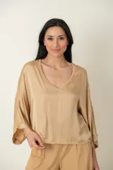 Blusa italiana de viscosa color beige, con escote en V ribeteado con lurex, mangas tres cuartos amplias y calce holgado.