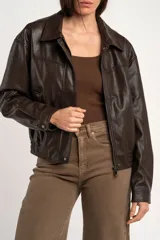 Campera bomber de cuero sintético marrón, con cierre frontal, cuello camisero, bolsillos laterales y elástico en los puños y la cintura.