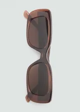 Gafas de sol de diseño rectangular con montura de pasta marrón traslúcida y lentes oscuras.