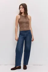 Musculosa blanca de ajuste ceñido con cuello redondo y detalle de apliques metálicos a lo largo de la parte frontal.