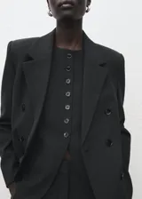 Chaleco de estilo sastre en color negro, con cuello redondo, cierre frontal de botones y diseño recto sin mangas.