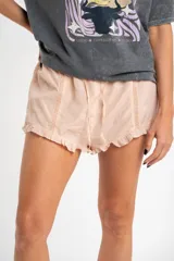Short de tiro medio color rosado pálido, confeccionado en tela ligera y delicada. Presenta detalles de encaje en los laterales y volados en el ruedo. Posee cordón ajustable en la cintura.