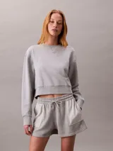 Buzo cropped de cuello redondo, confeccionado en algodón regenerativo, con puños y dobladillo en punto canalé y detalle de insignia con logotipo de la marca.