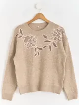 Sweater de punto color beige con cuello redondo, manga larga y detalle de bordado floral en la parte superior del pecho.