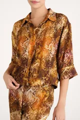 Camisa de viscosa con estampado animal print tipo piel de serpiente en tonos marrones y rojizos, de corte corto, manga larga y cuello clásico.