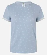 Blusa de pijama de mujer color celeste, confeccionada en tejido peach touch de poliéster con elastano, con estampado de moños sutiles. Presenta cuello redondo, mangas cortas con detalles de encaje blanco y un pequeño moño decorativo en el escote.