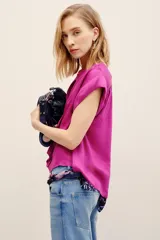 Camisa sin mangas de corte amplio y color fucsia, con cuello mao y cierre frontal de botones ocultos.
