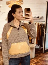 Sweater gris con diseño acolchado, cuello alto con cierre parcial y detalles en cuero amarillo bordado a mano en laterales y bolsillo frontal.