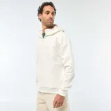 Buzo de felpa color blanco crudo, con capucha ajustable mediante cordones, cierre frontal parcial en el cuello y bolsillo tipo canguro. Presenta puños y ruedo acanalados.