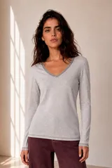 Remera gris melange de manga larga, con escote en V y detalles de ribete rayado en el cuello y los puños.