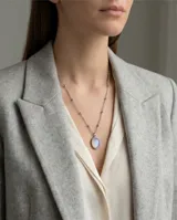 Collar de acero con cadena de eslabones finos con pequeñas esferas intercaladas y dije ovalado con piedra de la luna engarzada.