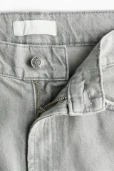 Jean barrel de tiro alto confeccionado en denim de algodón rígido color gris claro con efecto deslavado, diseño curvo en las piernas y tiras finas para anudar en los bajos.