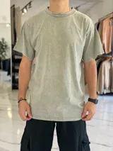 Remera oversize color verde militar con efecto gastado, cuello redondo y moldería amplia. Presenta una pequeña inscripción bordada en el pecho con la palabra 'underwave'.