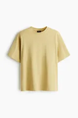 Remera de algodón pesado color beige, con cuello redondo ribeteado, hombros caídos y mangas cortas.