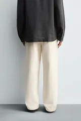 Pantalón de corte regular fit confeccionado en tejido de algodón con textura de espiga. Presenta cintura con pliegues frontales, bolsillos laterales y bolsillos traseros de vivo con botón. Cierre frontal con cremallera y botón.