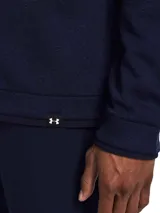 Buzo de cuello alto con cierre frontal de un cuarto, confeccionado en tejido polar elástico con tecnología UA Storm que repele el agua. Presenta un diseño de color azul marino con textura suave en el interior y detalles acanalados en puños y bajo.