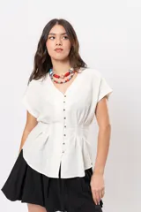 Blusa beige melange con escote en V, manga corta caída, botones metálicos frontales y pinzas que marcan la cintura.