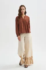 Pantalon ancho de algodón en color beige con detalle de bordado decorativo en el ruedo.