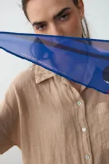 Pañuelo liviano y translúcido de diseño romboidal, con estampado inspirado en un atardecer uruguayo en tonos rosa, rojo y azul, ideal para usar atado al cuello.