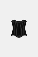 Top corsetero semitransparente con escote palabra de honor, detalle de varillas interiores y bajo asimétrico. Cuenta con cierre lateral con cremallera oculta.