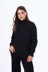 Buzo tejido de punto color negro, con cuello alto, manga larga y corte holgado con aberturas laterales en el ruedo.