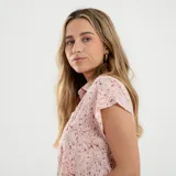 Camisa blanca con estampado de palmeras verdes y detalles en marrón.