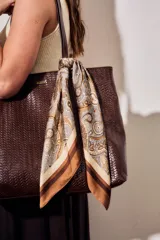 Bandana cuadrada de poliéster con estampado paisley en tonos marrones, beige y crudo, con bordes anchos en degradé marrón.