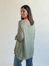 Sweater de tejido de punto color verde, de corte holgado y acampanado, con cuello redondo y mangas largas con presilla para arremangar.