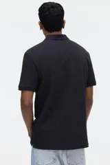 Remera polo de manga corta en piqué de algodón color negro, con cuello clásico y tapeta de dos botones. Corte estándar para una silueta clásica y cómoda.