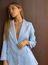 Blazer sastrero de lino color celeste pastel, con solapa clásica, cierre frontal con un botón y bolsillos con solapa en los laterales.