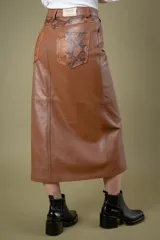 Pollera midi de cuero ovino con diseño tipo jean, cierre frontal con botón y tajo central.