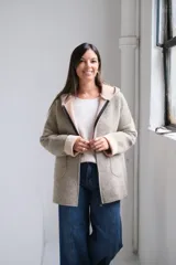 Tapado de paño con capucha, color beige, con cierre frontal, bolsillos laterales y puños vueltos en tono más claro.