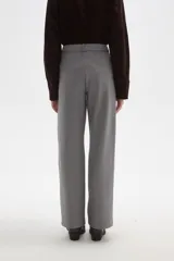 Pantalon de vestir gris de corte recto y tiro alto, con pinzas frontales y cierre de botón y cremallera.