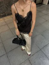 Blusa de satén negro con delicados breteles finos y terminaciones de encaje en el escote y el ruedo, de silueta fluida y calce relajado.