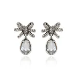 Aros colgantes plateados de estilo vintage con diseño de lazo decorado con pedrería y un dije en forma de lágrima con cristal facetado.