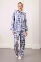 Conjunto de dos piezas compuesto por una camisa de manga larga con cuello camisero y botones frontales, y un pantalón de corte recto. Ambas prendas presentan un estampado geométrico de círculos bicolores.