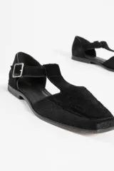 Zapato guillermina de cuero con pelo negro, con punta cuadrada, tira sobre el empeine con hebilla metálica y suela plana.